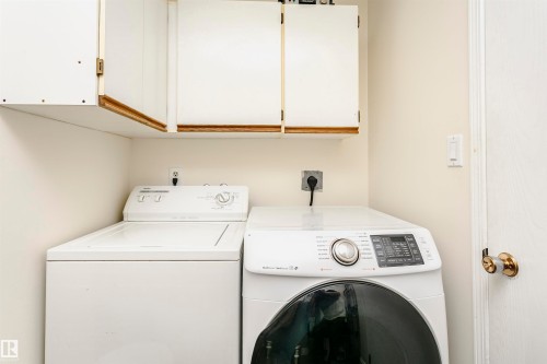 Dedicated laundry space featuring upper cabinetry with wood trim - 303 10026 112 Street, Edmonton, AB - Indoor Photo Showing Laundry Room
