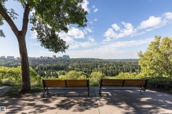 Paved patio area featuring two wooden benches with metal frames, set against a backdrop of extensive forested landscapes - 
