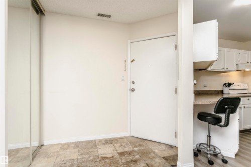 Entryway featuring stone-look tile flooring, white baseboards, and a mirrored sliding closet door - 303 10026 112 Street, Edmonton, AB - Indoor Photo Showing Other Room