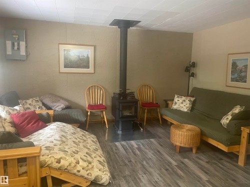 Living area featuring wood-finish flooring, a central freestanding wood-burning stove, and neutral wall tones - 650031 Range Road 185, Rural Athabasca County, AB 