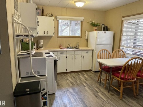 Kitchen featuring wood-finish flooring, white cabinetry, a double basin sink, and a built-in range - 650031 Range Road 185, Rural Athabasca County, AB 