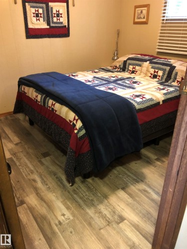 Bedroom featuring wood-finish flooring, neutral-toned walls, and a window with horizontal blinds - 650031 Range Road 185, Rural Athabasca County, AB 