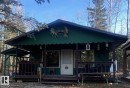 Green exterior cabin featuring a covered front porch with dark wood railing - 650031 Range Road 185, Rural Athabasca County, AB 