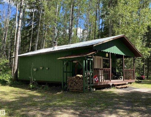 Green-sided structure featuring a covered front porch with wood railings and steps - 650031 Range Road 185, Rural Athabasca County, AB 