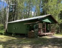 Green-sided structure featuring a covered front porch with wood railings and steps - 650031 Range Road 185, Rural Athabasca County, AB 