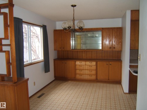 Dining area featuring a built-in wood-finish cabinet system with glass-front display, multiple drawers, and under-cabinet storage - 5030 52 Avenue, Andrew, AB - Indoor Photo Showing Other Room