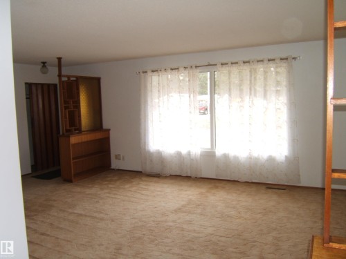 Spacious room with plush carpet flooring and a large window providing ample natural light - 5030 52 Avenue, Andrew, AB - Indoor