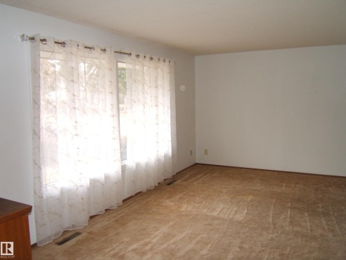 Bright room with light-colored walls and brown carpeting - 5030 52 Avenue, Andrew, AB - Indoor Photo Showing Other Room