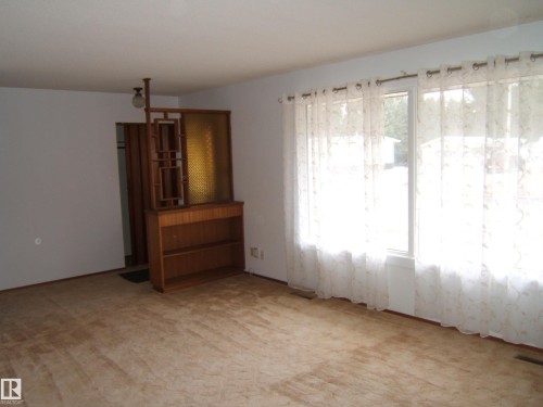 Bright interior space featuring a large picture window with sheer curtains - 5030 52 Avenue, Andrew, AB - Indoor Photo Showing Other Room