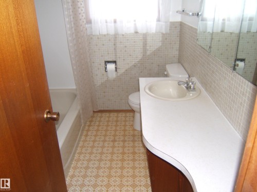 Bathroom with patterned floor tile, full bathtub, and a vanity featuring an integrated sink and mirror - 5030 52 Avenue, Andrew, AB - Indoor Photo Showing Bathroom