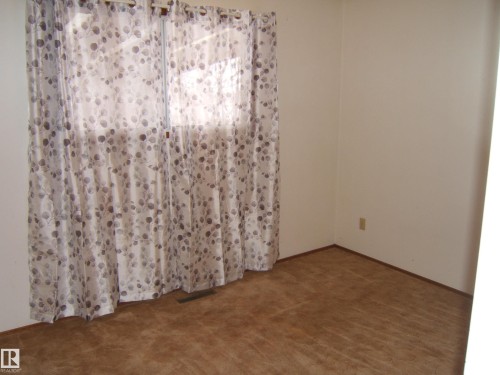 Neutral wall paint with brown baseboards and coordinating brown carpet - 5030 52 Avenue, Andrew, AB - Indoor Photo Showing Other Room