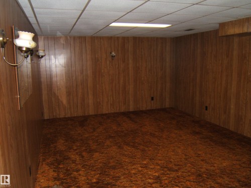 Room featuring wood-finish paneling, a textured brown carpet, and a drop ceiling with recessed lighting - 5030 52 Avenue, Andrew, AB - Indoor Photo Showing Other Room