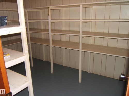 Storage room featuring extensive built-in shelving, painted paneling, and a painted floor - 5030 52 Avenue, Andrew, AB - Indoor With Storage