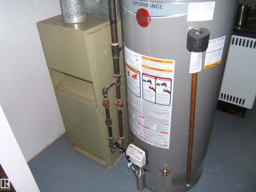 Water heater and furnace units with associated copper and galvanized piping - 5030 52 Avenue, Andrew, AB - Indoor Photo Showing Basement