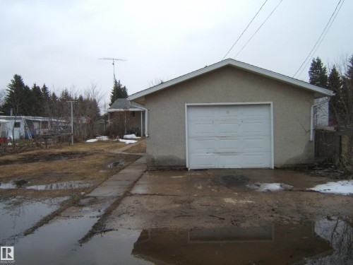 Detached garage with stucco exterior and a single white garage door - 5030 52 Avenue, Andrew, AB - Outdoor