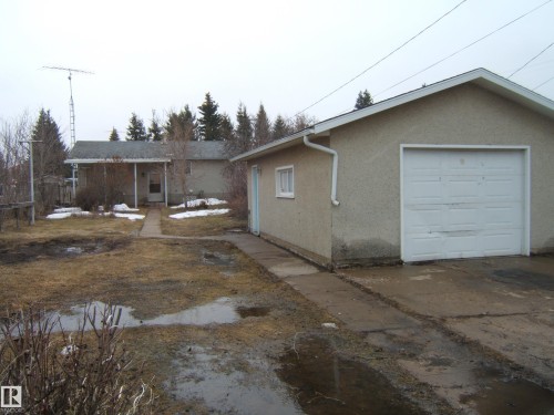 Detached single-car garage featuring stucco exterior and a white overhead door - 5030 52 Avenue, Andrew, AB - Outdoor