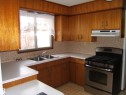Kitchen featuring wood-finish cabinetry, a stainless-steel range, dual basin sink, and mosaic tile backsplash - 5030 52 Avenue, Andrew, AB  - Indoor Photo Showing Kitchen With Double Sink 