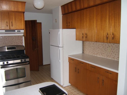 Kitchen featuring abundant wood-finish cabinetry, white countertops, and a mosaic tile backsplash - 5030 52 Avenue, Andrew, AB - Indoor Photo Showing Kitchen