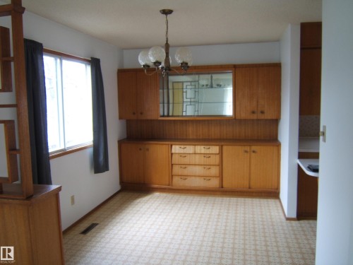 Dining area featuring a built-in wood-finish hutch with mirror accents, offering extensive storage - 5030 52 Avenue, Andrew, AB - Indoor
