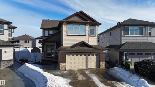 Two-story residence featuring light-toned siding, a dark shingled roof, and stone accents on the facade - 97 Astoria Point(E), Devon, AB - Outdoor With Facade