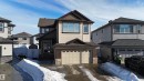 Two-story residence featuring light-toned siding, a dark shingled roof, and stone accents on the facade - 97 Astoria Point(E), Devon, AB  - Outdoor With Facade 