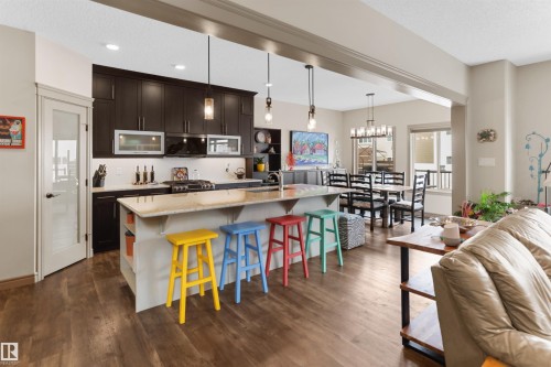 Spacious kitchen featuring dark wood cabinetry, a white subway tile backsplash, and a light-toned island with an integrated sink - 97 Astoria Point(E), Devon, AB - Indoor Photo Showing Kitchen With Upgraded Kitchen