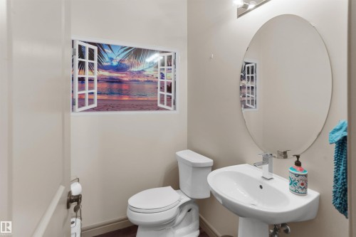 Bathroom featuring a pedestal sink with a chrome faucet, oval wall mirror, and toilet - 97 Astoria Point(E), Devon, AB - Indoor Photo Showing Bathroom