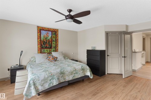 Bedroom featuring wood-finish flooring, a contemporary ceiling fan, and light-toned walls - 97 Astoria Point(E), Devon, AB - Indoor Photo Showing Bedroom