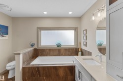 Soaking tub with surrounding wood-look tile, complemented by a large privacy window - 