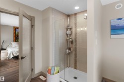 Glass-enclosed shower with subway tile surround, decorative mosaic tile accent, and recessed lighting - 