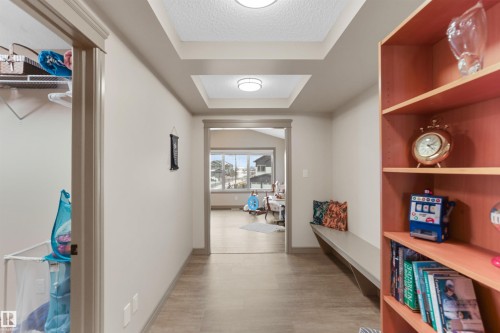 Hallway featuring recessed ceiling details with integrated lighting, wood-finish flooring, and a built-in bench - 97 Astoria Point(E), Devon, AB - Indoor Photo Showing Other Room