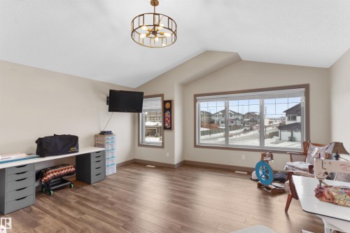 Spacious room featuring vaulted ceilings, wood-finish flooring, and a large multi-pane window - 97 Astoria Point(E), Devon, AB - Indoor