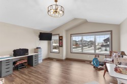 Spacious room featuring vaulted ceilings, wood-finish flooring, and a large multi-pane window - 