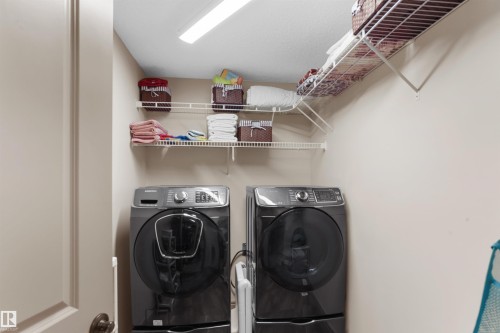 Laundry area featuring a side-by-side washer and dryer, wire shelving, and overhead lighting - 97 Astoria Point(E), Devon, AB - Indoor Photo Showing Laundry Room