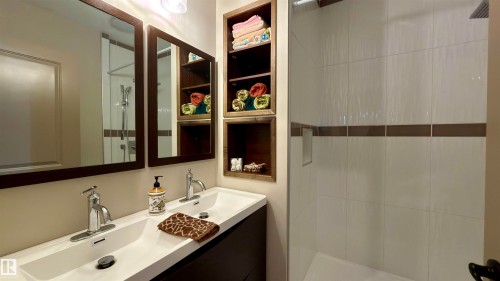 Modern bathroom featuring a double vanity with integrated sinks, chrome faucets, and dark wood-finish cabinetry - 97 Astoria Point(E), Devon, AB - Indoor Photo Showing Bathroom