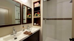 Modern bathroom featuring a double vanity with integrated sinks, chrome faucets, and dark wood-finish cabinetry - 