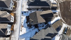 Aerial perspective showcasing a residential neighborhood with dark shingle roofs, individual driveways, and concrete curbing - 