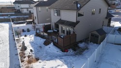 Rear exterior featuring a multi-level composite deck with privacy screens and glass railings, a white vinyl fence, and an exterior storage shed - 