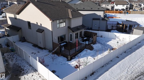 Expansive fenced backyard featuring a multi-level wooden deck with glass panel railings, a separate covered patio structure, and a storage shed - 97 Astoria Point(E), Devon, AB - Outdoor With Deck Patio Veranda
