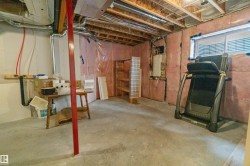 Unfinished basement space featuring exposed joists, concrete flooring, and an egress window - 