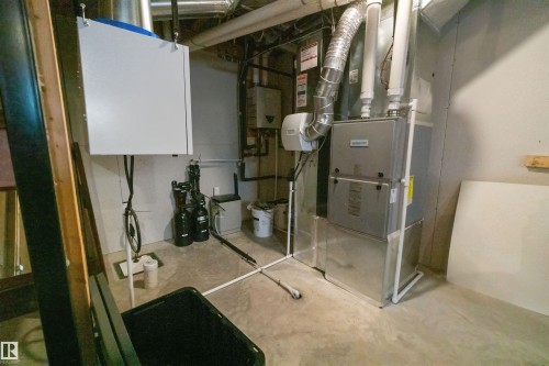 Utility area with concrete flooring, showcasing a furnace, water heater, water softener system, and an air purification unit - 97 Astoria Point(E), Devon, AB 