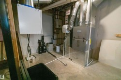 Utility area with concrete flooring, showcasing a furnace, water heater, water softener system, and an air purification unit - 