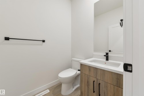 Bathroom featuring a wood-finish vanity with a white countertop and integrated sink, matte black faucet, and a large wall mirror - 162 Caldeon Crescent, Spruce Grove, AB - Indoor Photo Showing Bathroom