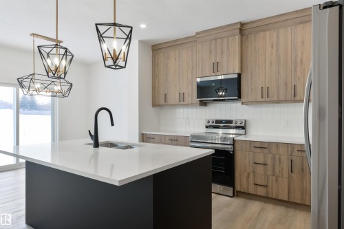 Contemporary kitchen with a central island featuring a stainless steel sink and matte black faucet - 162 Caldeon Crescent, Spruce Grove, AB - Indoor Photo Showing Kitchen With Double Sink With Upgraded Kitchen