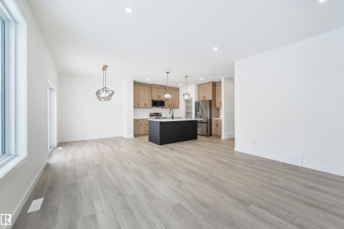 Open-concept living area featuring light wood-finish flooring, recessed lighting, and a modern geometric pendant fixture - 162 Caldeon Crescent, Spruce Grove, AB - Indoor Photo Showing Kitchen