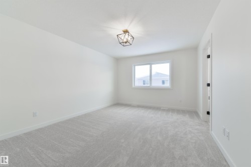 Bright room featuring light grey patterned carpeting, a central window with white trim, and a modern geometric ceiling light fixture - 162 Caldeon Crescent, Spruce Grove, AB - Indoor Photo Showing Other Room
