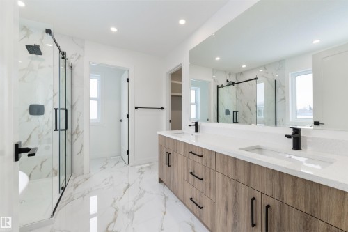Contemporary bathroom featuring a spacious dual-sink vanity with wood-finish cabinetry, a large frameless mirror, and a walk-in shower with a glass enclosure - 162 Caldeon Crescent, Spruce Grove, AB - Indoor Photo Showing Bathroom
