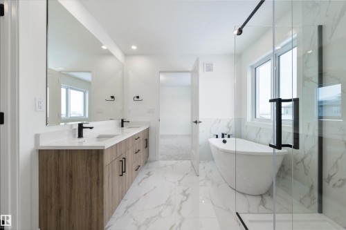 Spacious bathroom featuring a freestanding tub, glass-enclosed shower, dual vanity with wood-finish cabinetry, and large format marble-look tile flooring - 162 Caldeon Crescent, Spruce Grove, AB - Indoor Photo Showing Bathroom