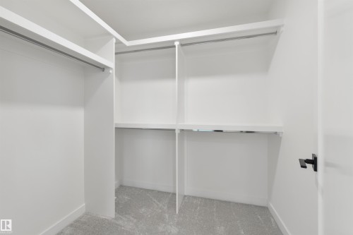 Closet featuring white shelving, multiple hanging rods, built-in storage, and light gray carpet flooring - 162 Caldeon Crescent, Spruce Grove, AB - Indoor With Storage