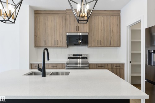 Kitchen featuring a double basin sink with a matte black faucet, light wood-finish cabinetry, white subway tile backsplash, and stainless steel appliances - 162 Caldeon Crescent, Spruce Grove, AB - Indoor Photo Showing Kitchen With Double Sink With Upgraded Kitchen